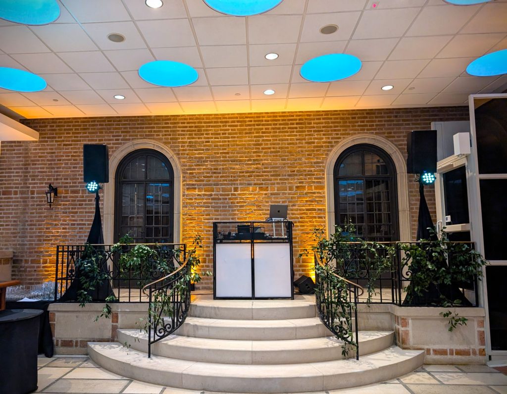 DJ booth set up on a courtyard stage with warm uplighting