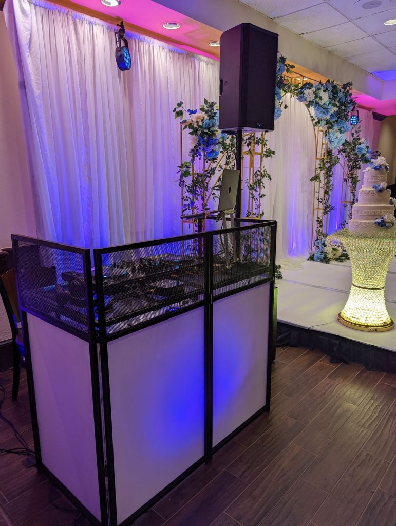 DJ booth with pink uplighting and floral decor