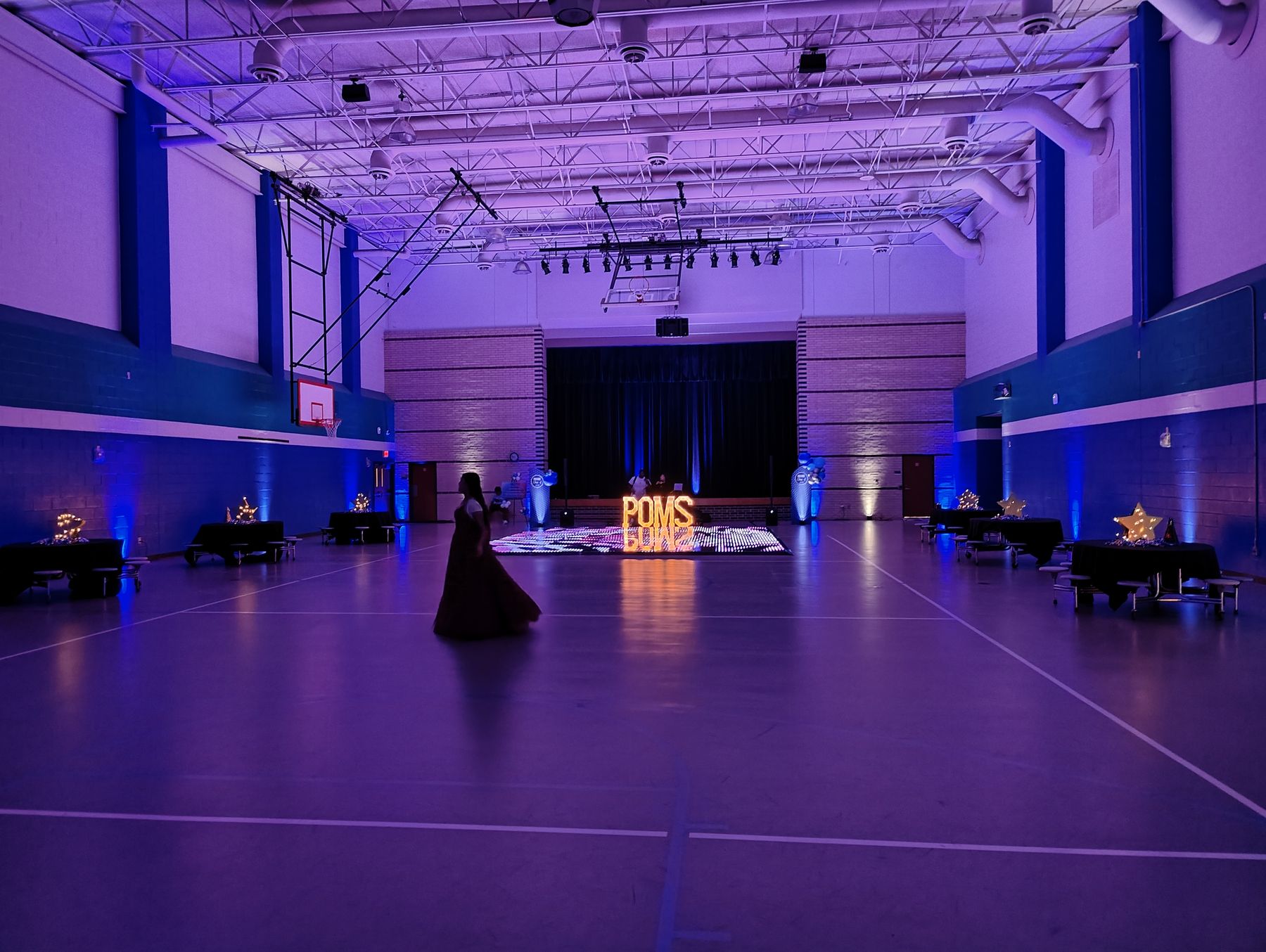 Event hall washed in purple and blue uplighting with an open dance floor