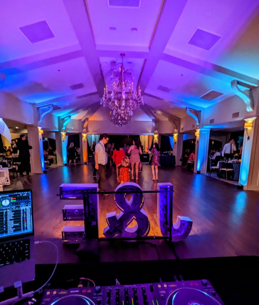 Marquee letters with initials glowing under purple uplighting