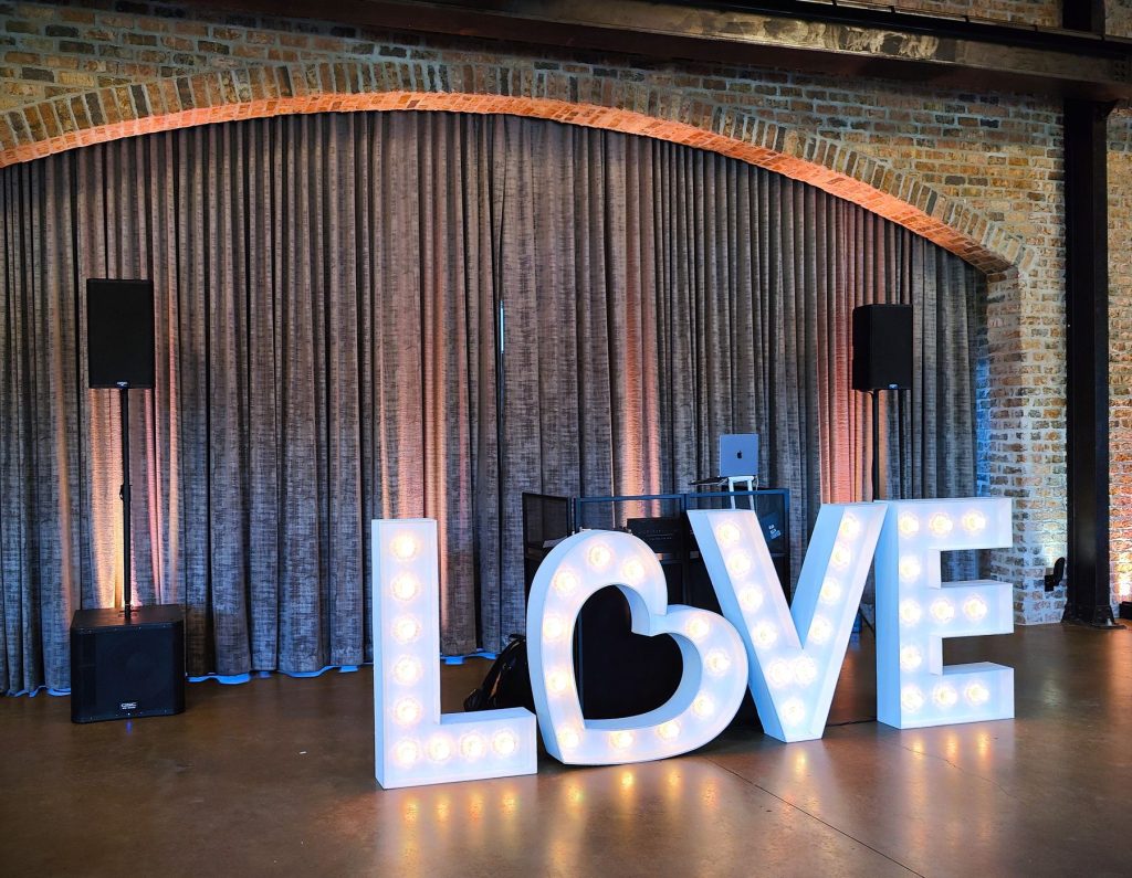 Lit LOVE marquee letters in front of a draped stage