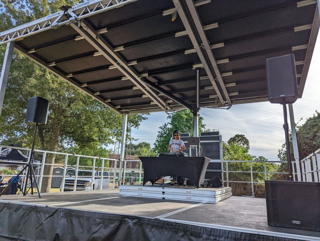 Covered outdoor stage with DJ booth and speakers set up