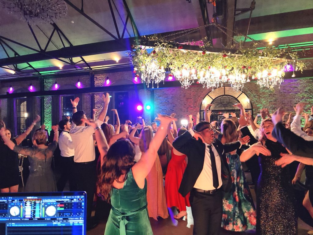 Packed dance floor with guests dancing under colorful party lighting