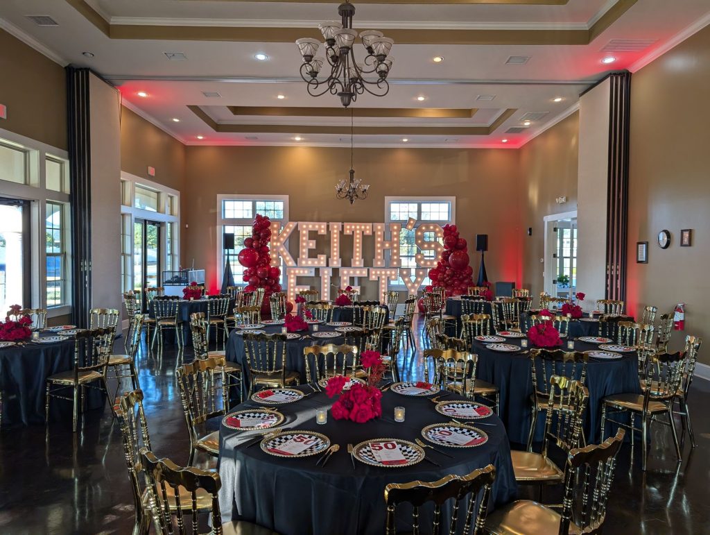 Reception hall with red uplighting, a chandelier and lit marquee letters
